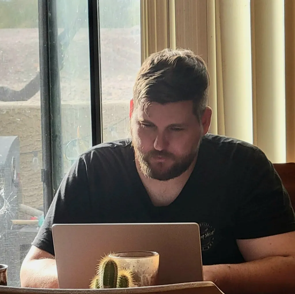 Founder, David Snow, sitting at a table working on a laptop with a cactus in front of him.